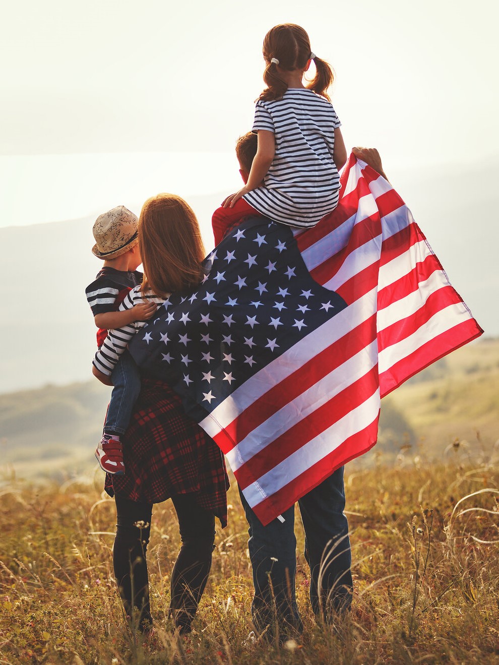 Happy family, parents and children with American flag outdoors